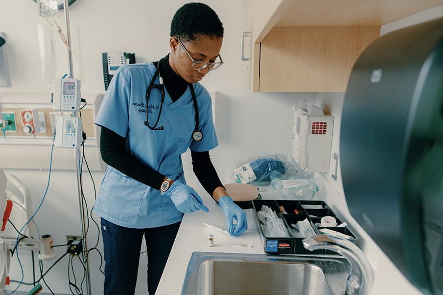 Nursing student examines equipment in lab.